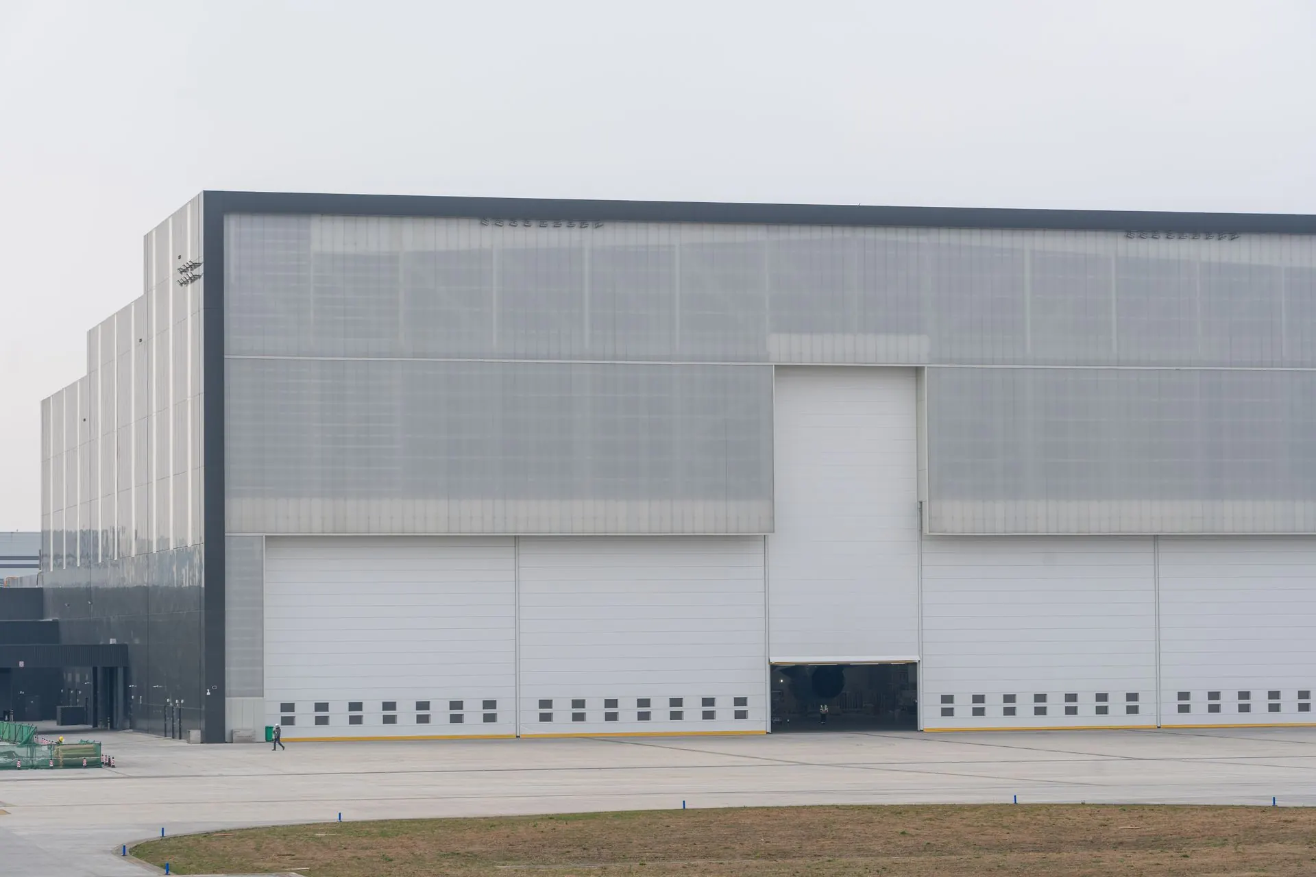 Large industrial facility with metal cladding, tall access doors, and a concrete apron.